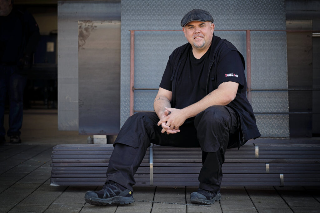 Metallbauer Franz Anian Nirschl sitzend vor seiner Firma
